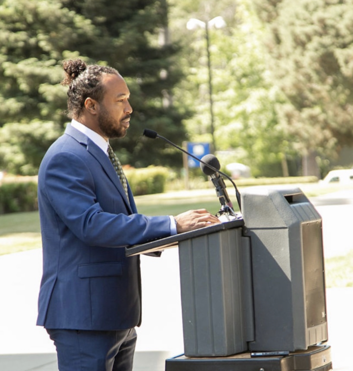 Madison Shockley III speaking at a press conference podium, advocating for cannabis equity policy